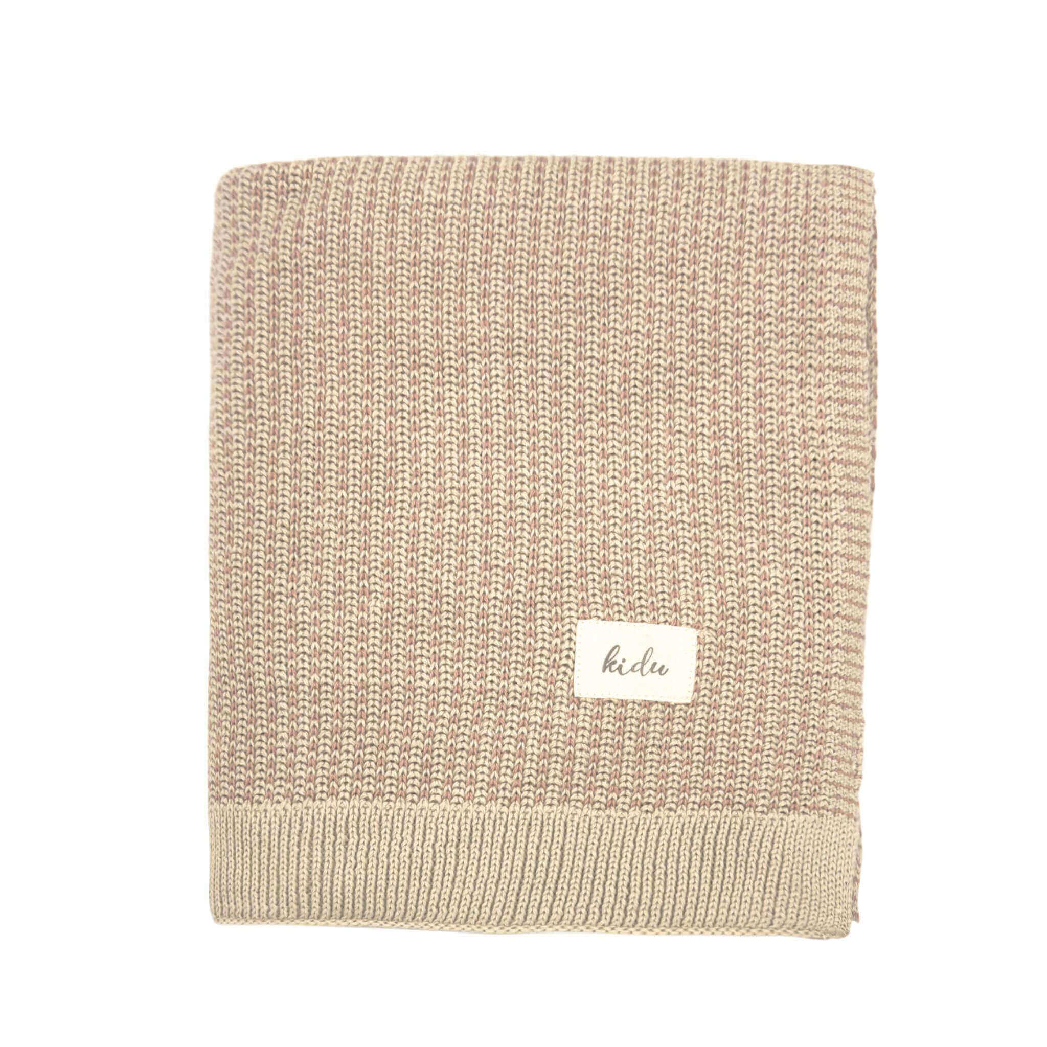 Beige and pink knitted organic cotton blanket with a visible kidu brand label on a white background